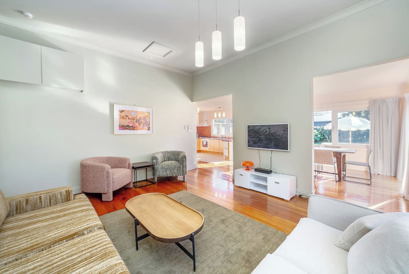 A modern living room with a sofa, armchair, coffee table, and a flat-screen TV.