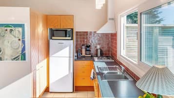 A modern kitchen with a refrigerator, microwave, and stove. There is a window providing natural light and a view of the outside.