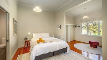 A bedroom with a bed, bedside table, lamp, and a window with a view.