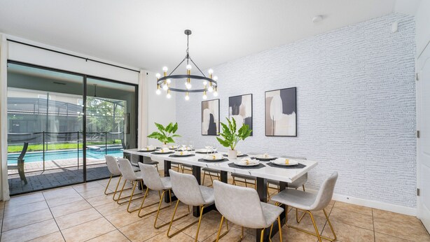Un espace repas comprenant une longue table, des chaises et un lustre.