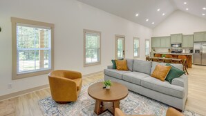 Un salon spacieux avec un canapé gris, une table basse ronde en bois et un tapis à motifs.