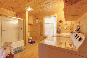 Een houten badkamer in een vakantiehuisje, met douche, toilet en wasmachine.