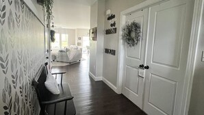 A hallway with a bench, a hanging light fixture, a door with a wreath, and a wall with a leaf-patterned wallpaper. - Tranquil 4-bedroom in charming Boalsburg, close to Beaver Stadium (Boalsburg)