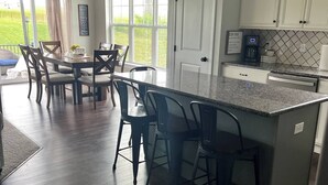 A modern kitchen with a central island, bar stools, a dining table with chairs, and a view of the outdoors. - Tranquil 4-bedroom in charming Boalsburg, close to Beaver Stadium (Boalsburg)