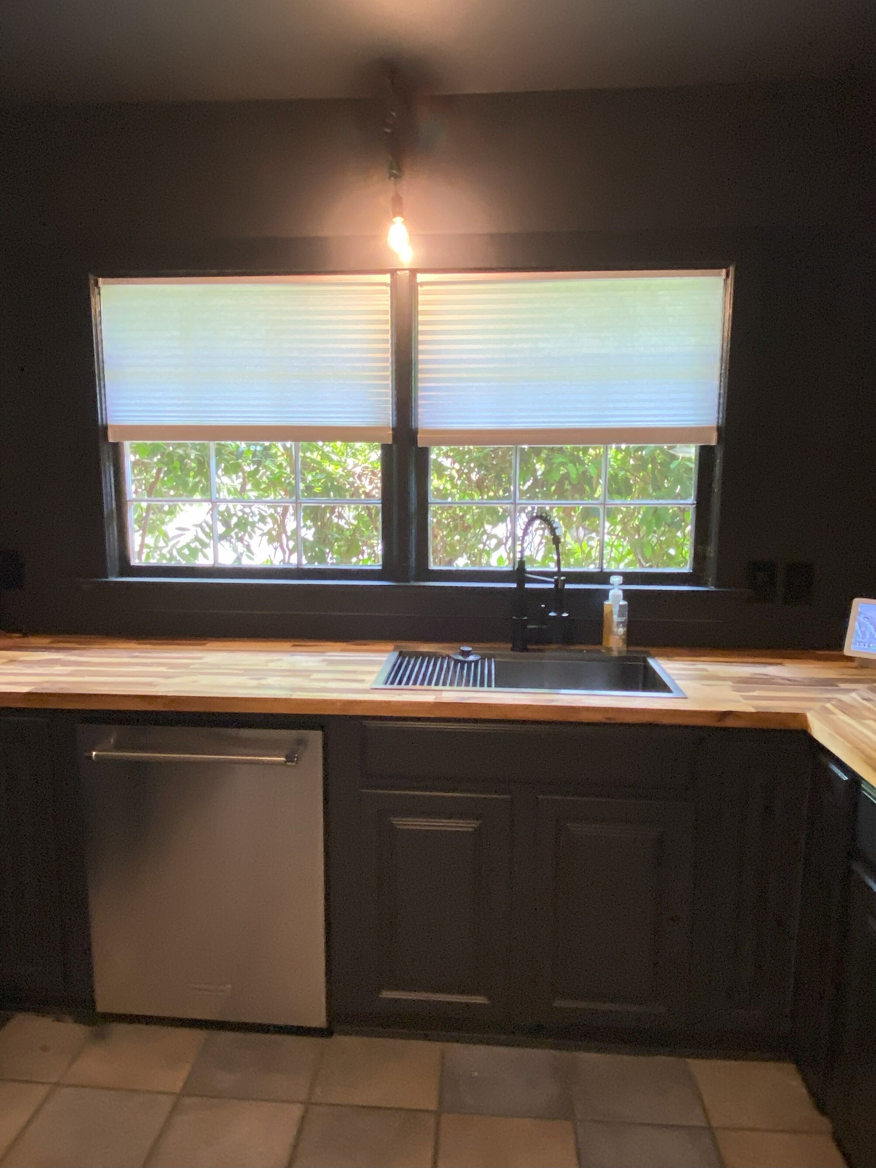 Una cocina con ventana, un lavamanos y un lavavajillas.