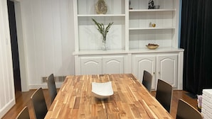 A dining room with a wooden table and chairs, a white cabinet with shelves, and a small vase with greenery. - Welcoming 4-bedroom house in vibrant Buckhead Atlanta (Atlanta)