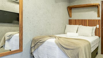 Une chambre à coucher avec une tête de lit en bois, un lit avec une literie blanche et un miroir au mur.