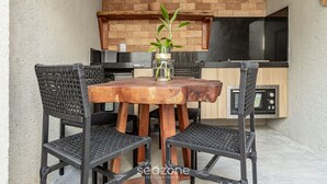 Ein Holztisch mit vier Stühlen, ein kleiner Blumentopf und eine Küchenzeile mit einer Mikrowelle und Schränken.
