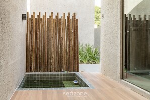 Un espace spa doté d’un paravent en bois pour plus d’intimité, d’un sol carrelé et d’une porte en verre.