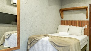 Ein Schlafzimmer mit einem hölzernen Kopfteil, einem Bett mit weißer Bettwäsche und einem Spiegel an der Wand.