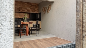 Eine Küche mit Ziegelwand, schwarzer Arbeitsplatte und Holztisch mit Stühlen.