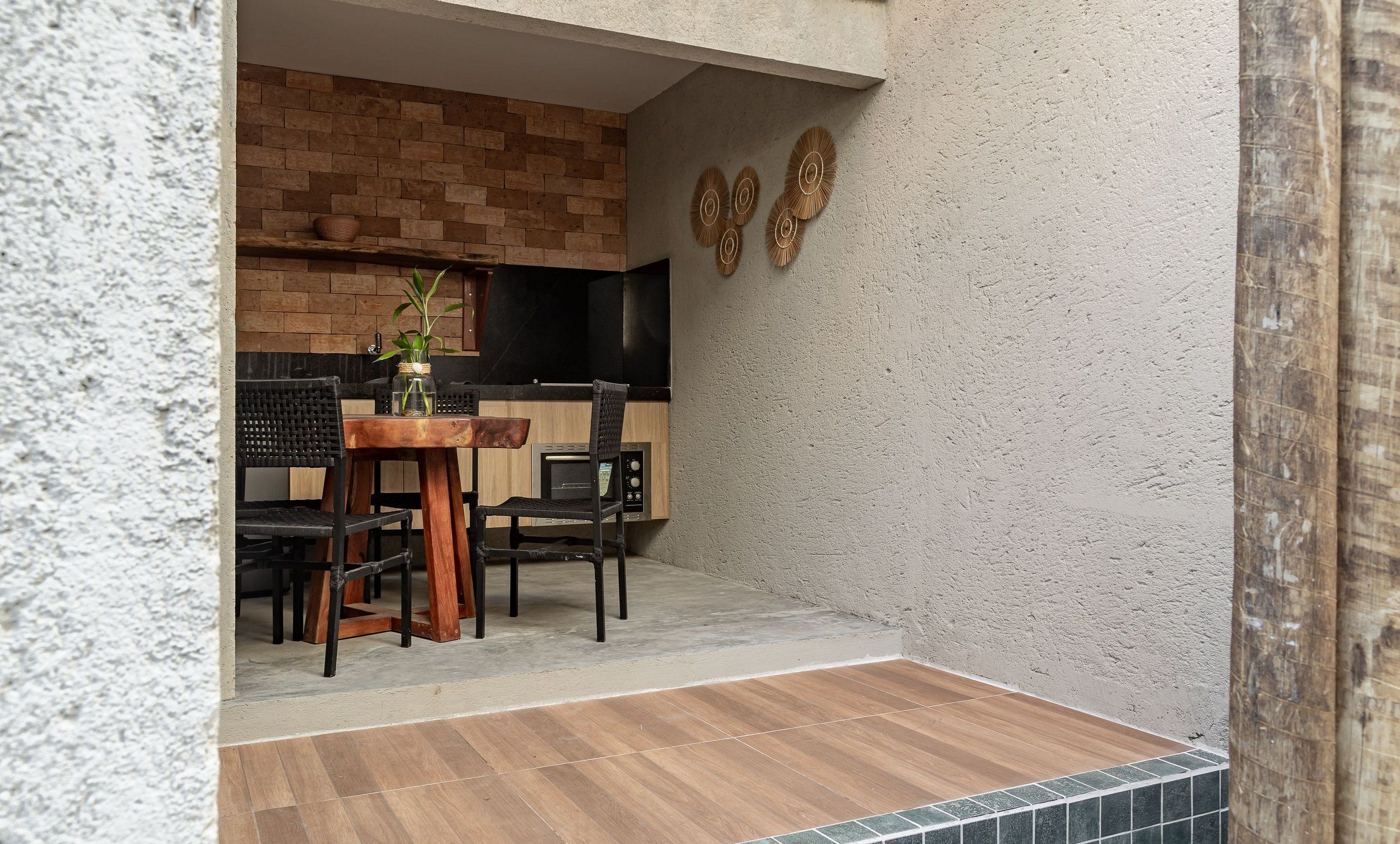 Een keuken met een bakstenen muur, een zwart aanrecht en een houten tafel met stoelen.