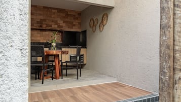 Une cuisine avec un mur en briques, un plan de travail noir et une table en bois avec des chaises.