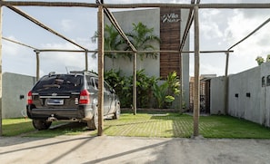 A black SUV parked in a covered parking area with a concrete wall and a sign reading "Villa Natur". - Apt With Pool and Barbecue Vnr005 (São Miguel dos Milagres)