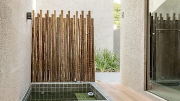 Un espace spa doté d’un paravent en bois pour plus d’intimité, d’un sol carrelé et d’une porte en verre.