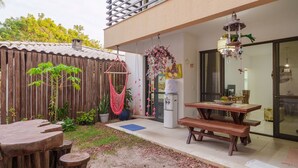 A patio area with a wooden table and benches, a hanging chair, and a refrigerator. - Comfortable apt With Pool Near the Beach Vrl0002 (Camaçari)