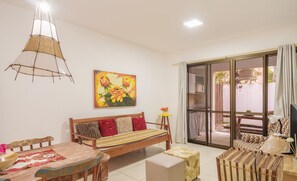 A cozy living room with a wooden sofa, a dining table, and a hanging light fixture. - Comfortable apt With Pool Near the Beach Vrl0002 (Camaçari)