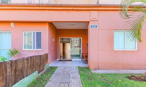 A building with a pink facade, a wooden fence, and a small garden area. - Condominium With a Pool 850m From Praia do Sul, Ilheus/ba VGT (Ilhéus)