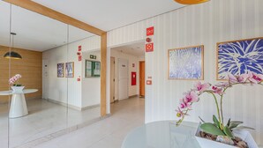 A hallway with a glass partition, framed artwork, and a potted orchid. - Condominium With a Pool 850m From Praia do Sul, Ilheus/ba VGT (Ilhéus)