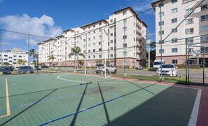 A basketball court with a chain-link fence, surrounded by multi-story residential buildings. - Condominium With a Pool 850m From Praia do Sul, Ilheus/ba VGT (Ilhéus)