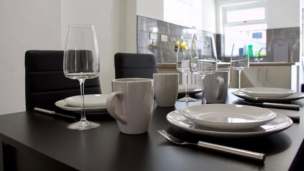 Una mesa de comedor con platos, vasos y una taza, y una silla al fondo.