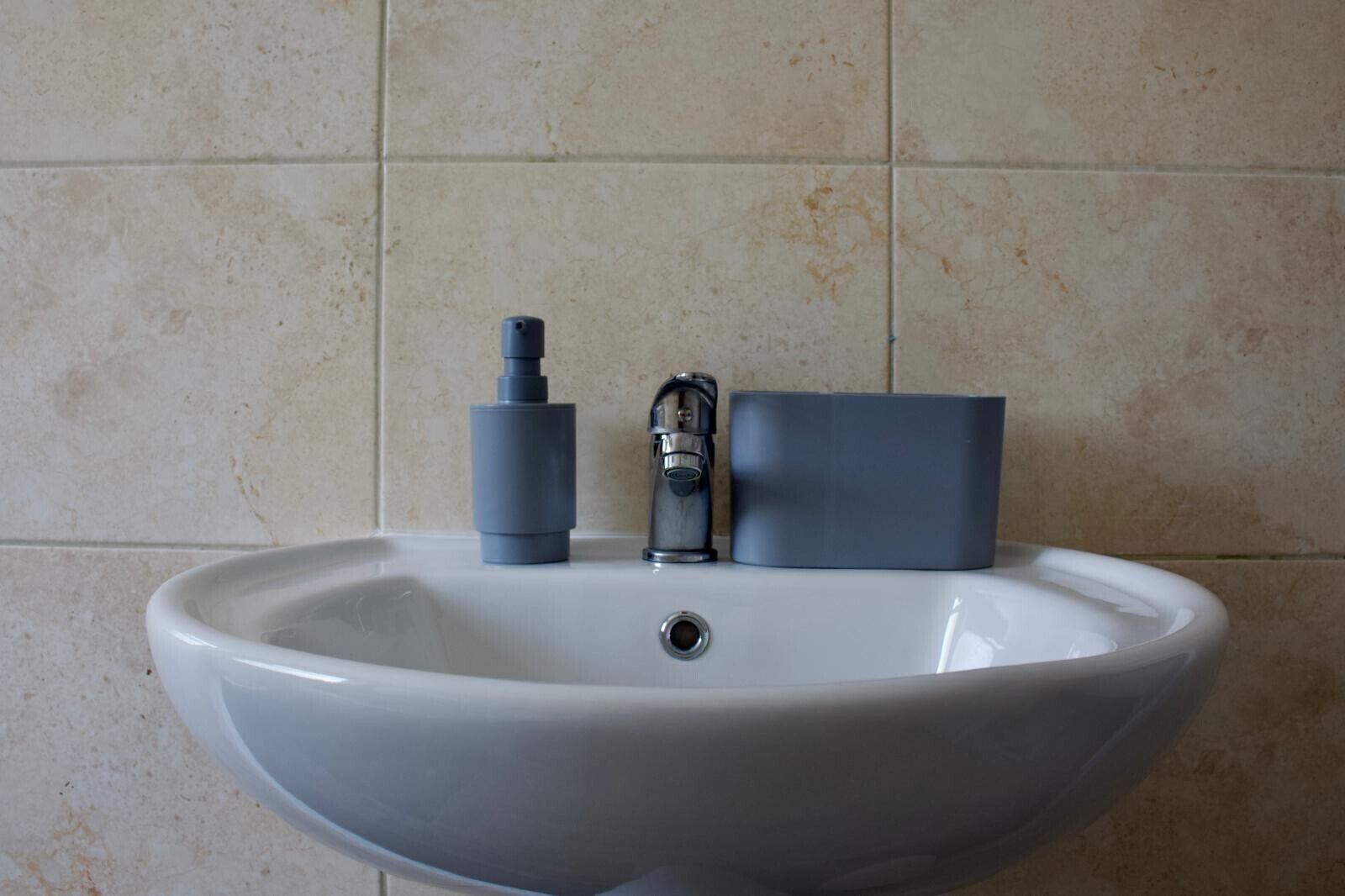 A white sink with a modern faucet and a soap dispenser.