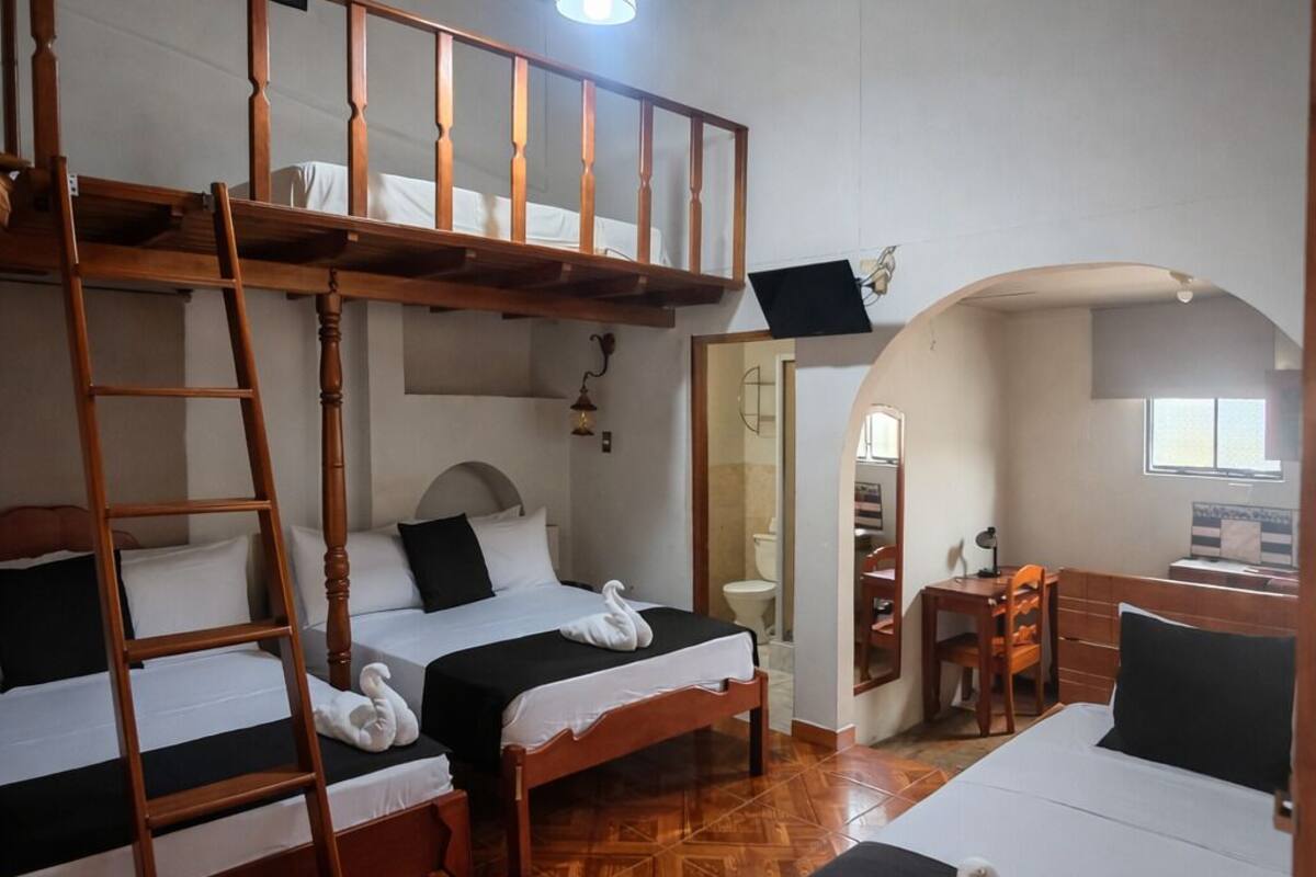 A room with bunk beds, a ladder, a desk, and a mirror.