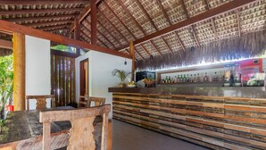 Zona de bar con mostrador de madera y techo de paja.