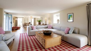 A spacious living room with a large sectional sofa, a coffee table, and a red and white checkered rug.