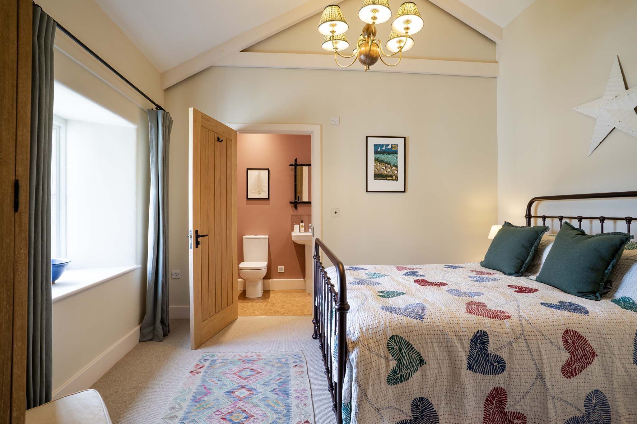 A bedroom with a bed, a window with curtains, a chandelier, and a star decoration on the wall.