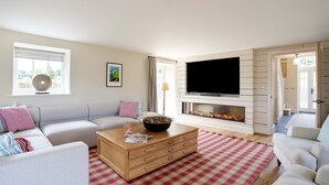 A living room with a fireplace, a flat-screen TV, and a checkered rug.