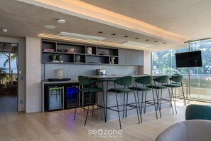 A modern kitchen with a bar area, built-in shelves, and a large window offering a view of the outdoors.
