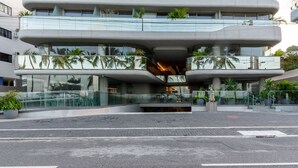A modern building with a unique architectural design featuring a central atrium and multiple balconies. - SYH - Complete Beachfront Condominium in Cabo Branco/pb (João Pessoa)