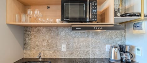 Una cocina equipada con microondas, cafetera y lavabo.