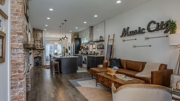 A spacious living area with a fireplace, a kitchen in the background, and a 'Music City' sign on the wall.