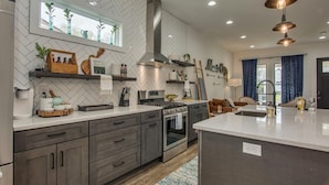 A modern kitchen with a herringbone tile backsplash, stainless steel appliances, and a central island.