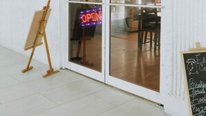 A coffee shop with a sign reading "Elites Coffee Shop" and a neon 'OPEN' sign.