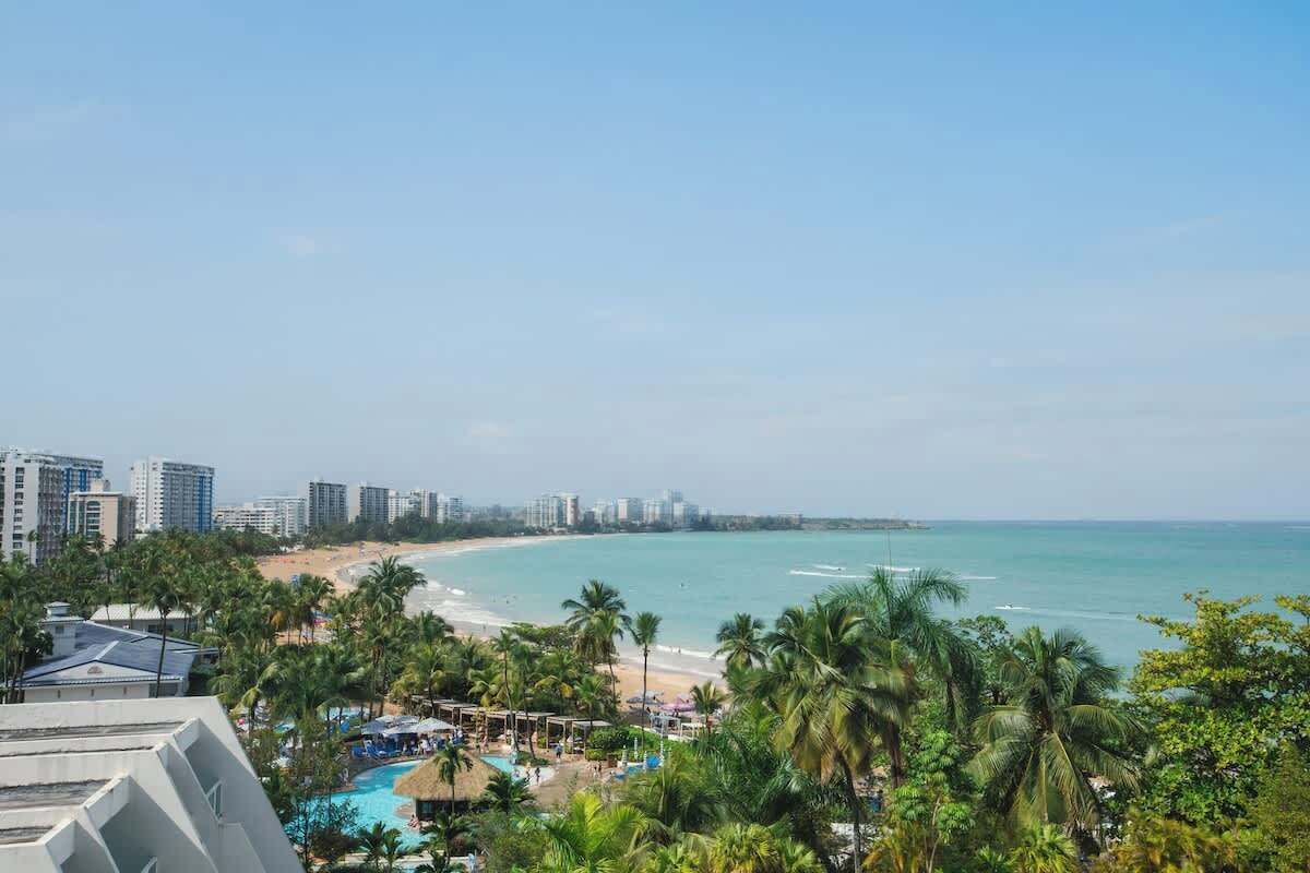 Un resort con vista a la playa, varias piscinas y palmeras.