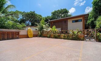 Un patio con piso de baldosas, una piscina inflable amarilla y un edificio con techo marrón y ventanas.