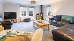 Een moderne woonkamer met een flatscreen televisie, leren banken, een houten salontafel en een open haard.