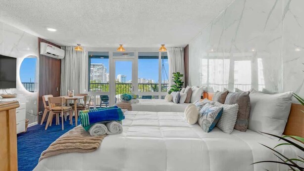 Et moderne hotelværelse med en stor seng, et spiseområde og en balkon med udsigt over byen.