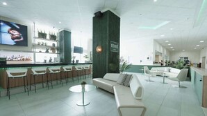 Un moderno vestíbulo de hotel con área de bar, zonas de estar y una pantalla grande.