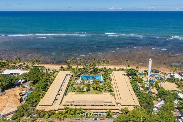 A resort with a large building, multiple swimming pools, and a beach area.