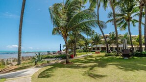 Ein Resort mit Blick auf den Strand, Palmen und einem Weg zu Sitzbereichen im Freien.