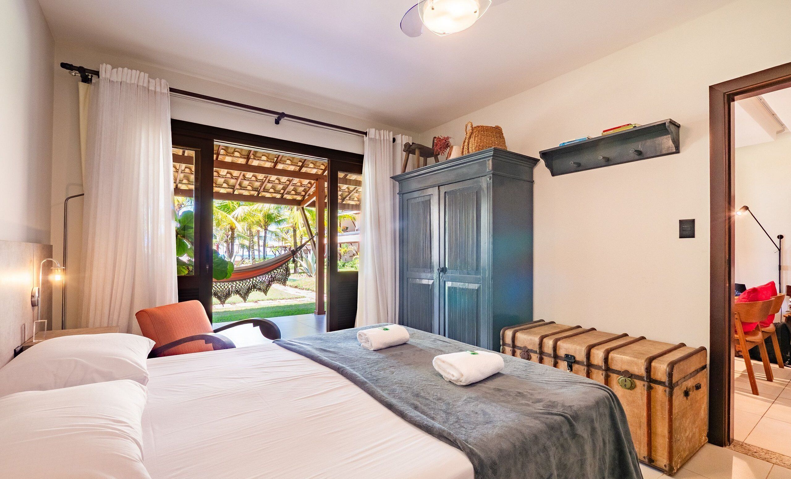Ein Hotelzimmer mit Bett, Hängematte, Schrank und Koffer.