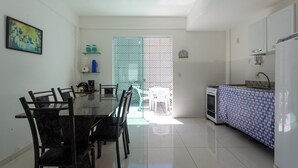 Una cocina moderna con comedor, que incluye una mesa con sillas, una cafetera y un refrigerador.
