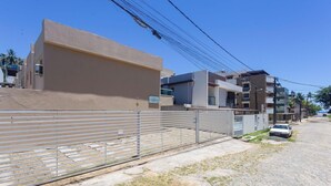 Una calle residencial con edificios modernos, un acceso con portón y un coche aparcado.