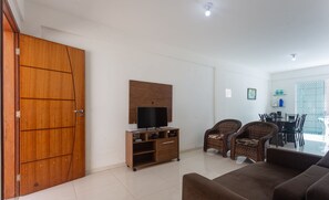A living room with a sofa, wicker chairs, a TV stand, and a dining area with chairs and a table. - Townhouse 300m From Ilheus Beach Vcm005 (Ilhéus)