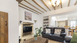 A cozy living room with a fireplace, a leather sofa, and a wooden coffee table. - Charming 3-Bed Cottage in Central Stroud (Gloucestershire)