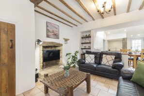 A cozy living room with a fireplace, a leather sofa, and a wooden coffee table.